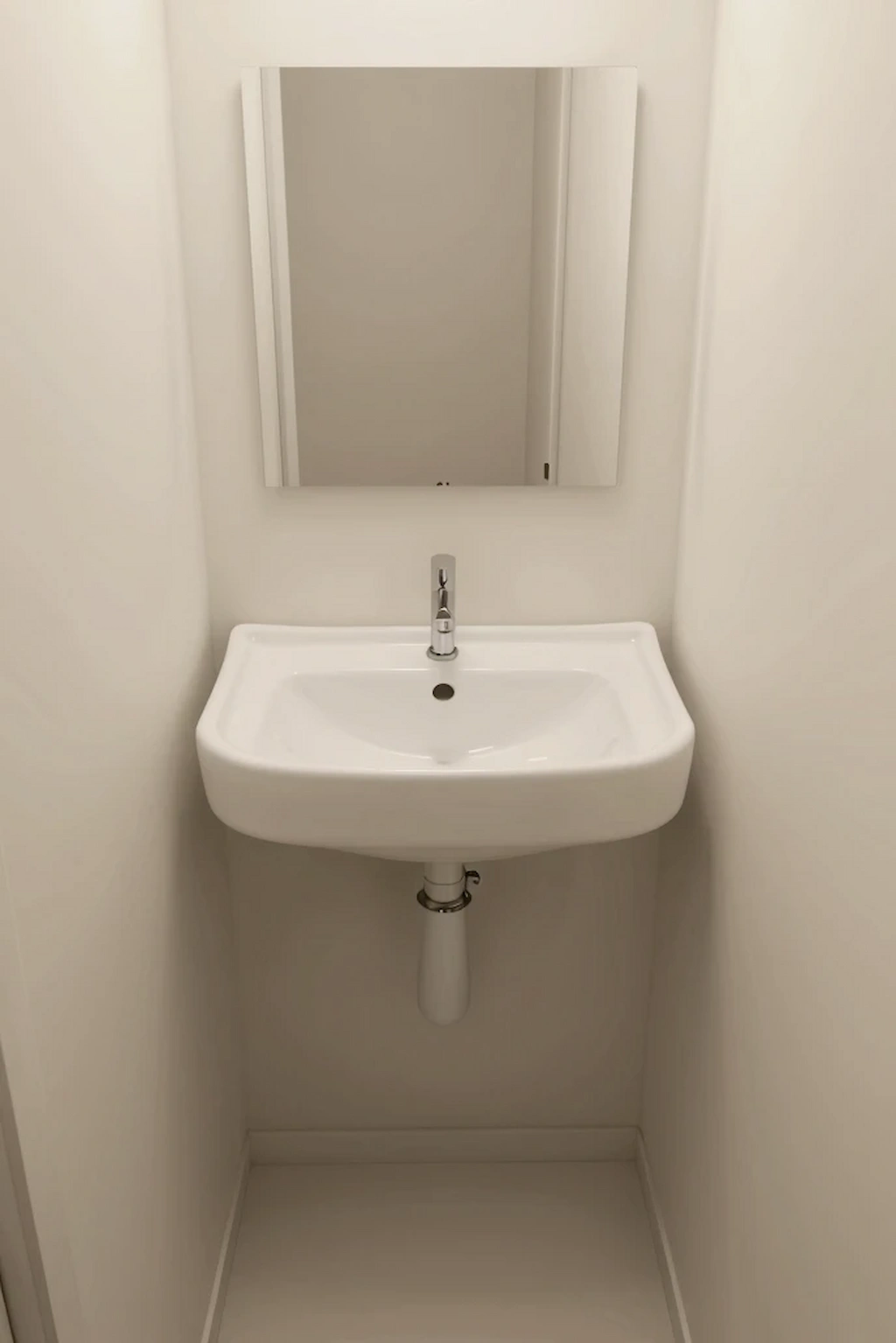 Small toilet room utilizing a corner sink to maximize floor space