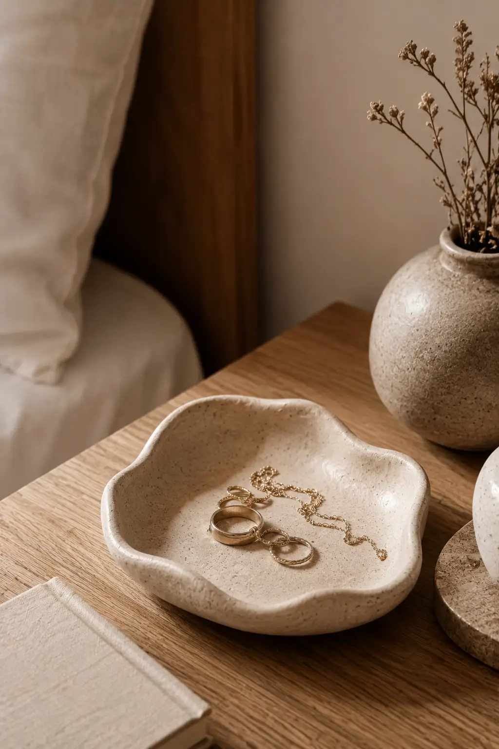 Handmade clay ring dish with organic edges holding jewelry on a modern bedside table